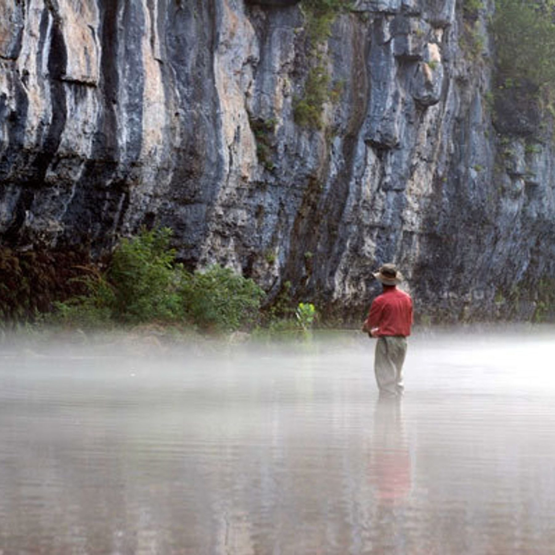 An angler standing in the mist on Spring Creek below the bluff